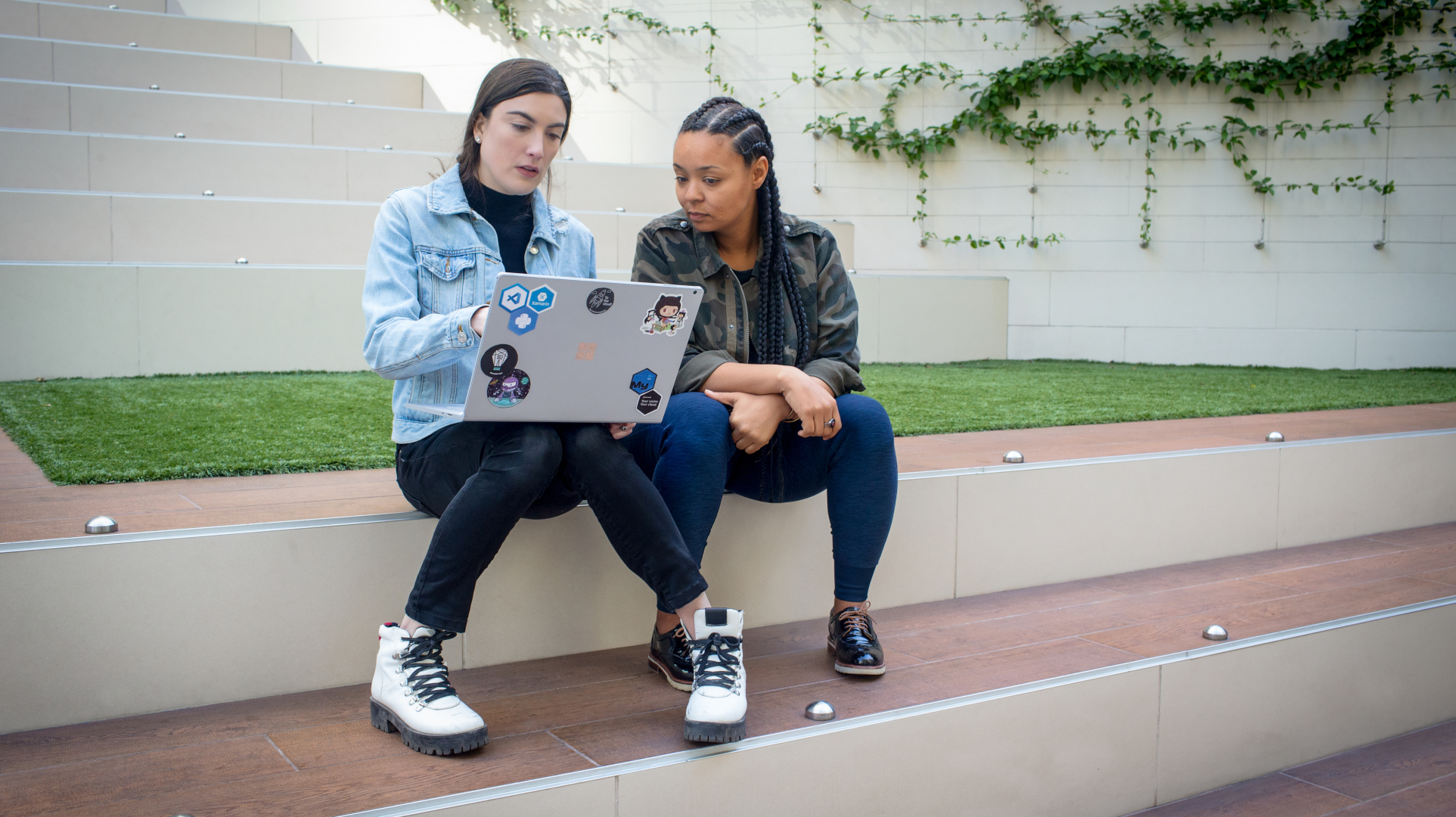 Two college students sitting on steps outside and working on a laptop together